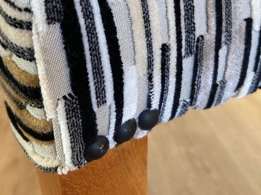 Finition du dossier au clou décoratif, sur un tissu rayé